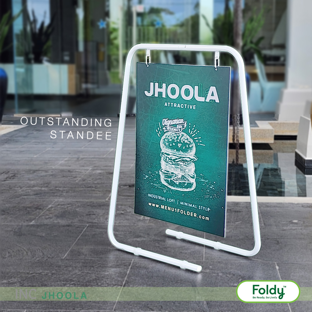 White A-frame sidewalk sign holding a teal JHOOLA poster advertising a vegetarian burger, outdoors on a paved plaza; Foldy logo at bottom right.