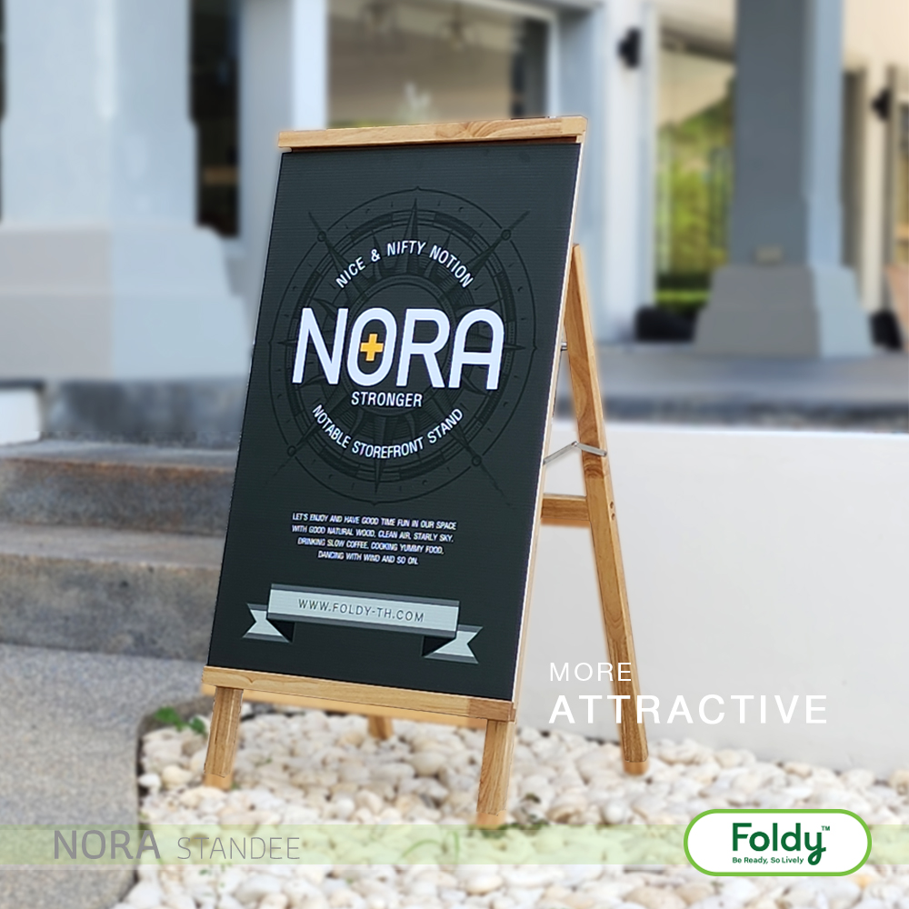 Outdoor chalkboard sign on a wooden easel displaying the NORA logo in white on a dark board, placed outside a building entrance (Foldy logo bottom right).